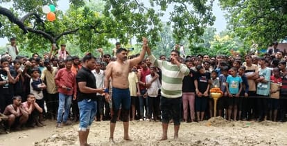 कुश्ती जीतने के बाद विजेता खिलाड़ी का हाथ उठाकर विजेता घोषित करता आयोजक। संवाद