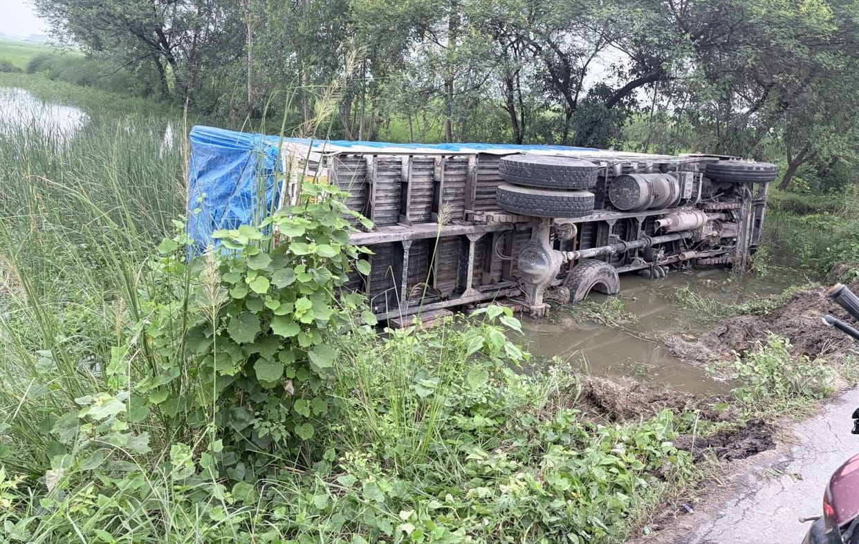 Roadside soil collapsed in the rain; loaded truck overturned into the pit.