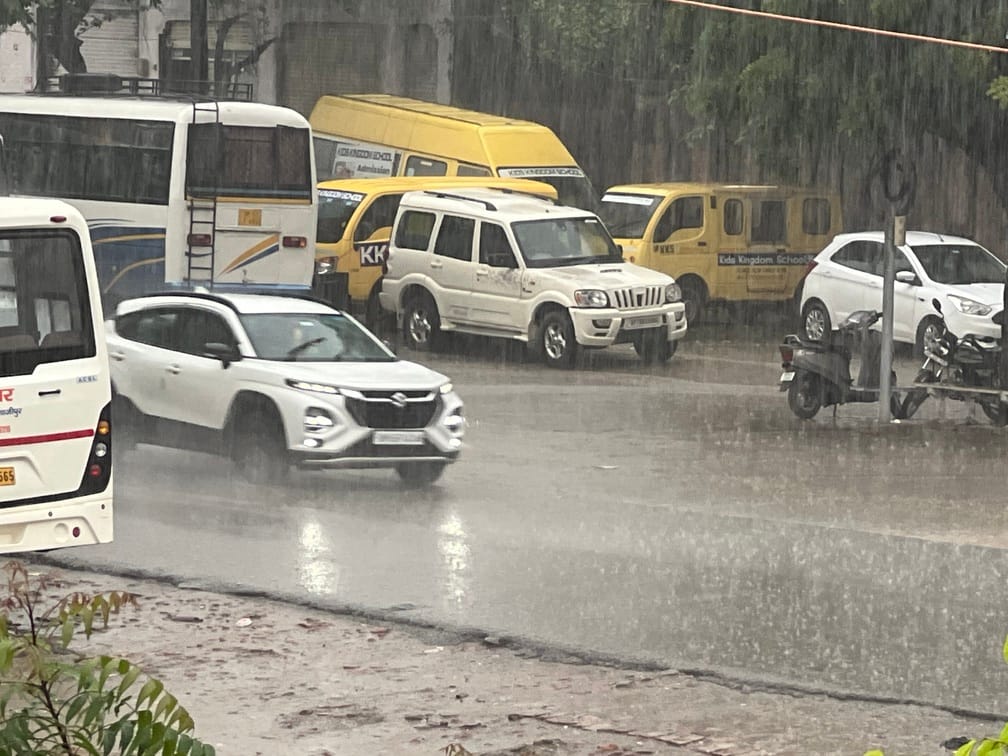 नगर में रविवार को हुई झमाझम बारिश के बीच जाती कार। संवाद