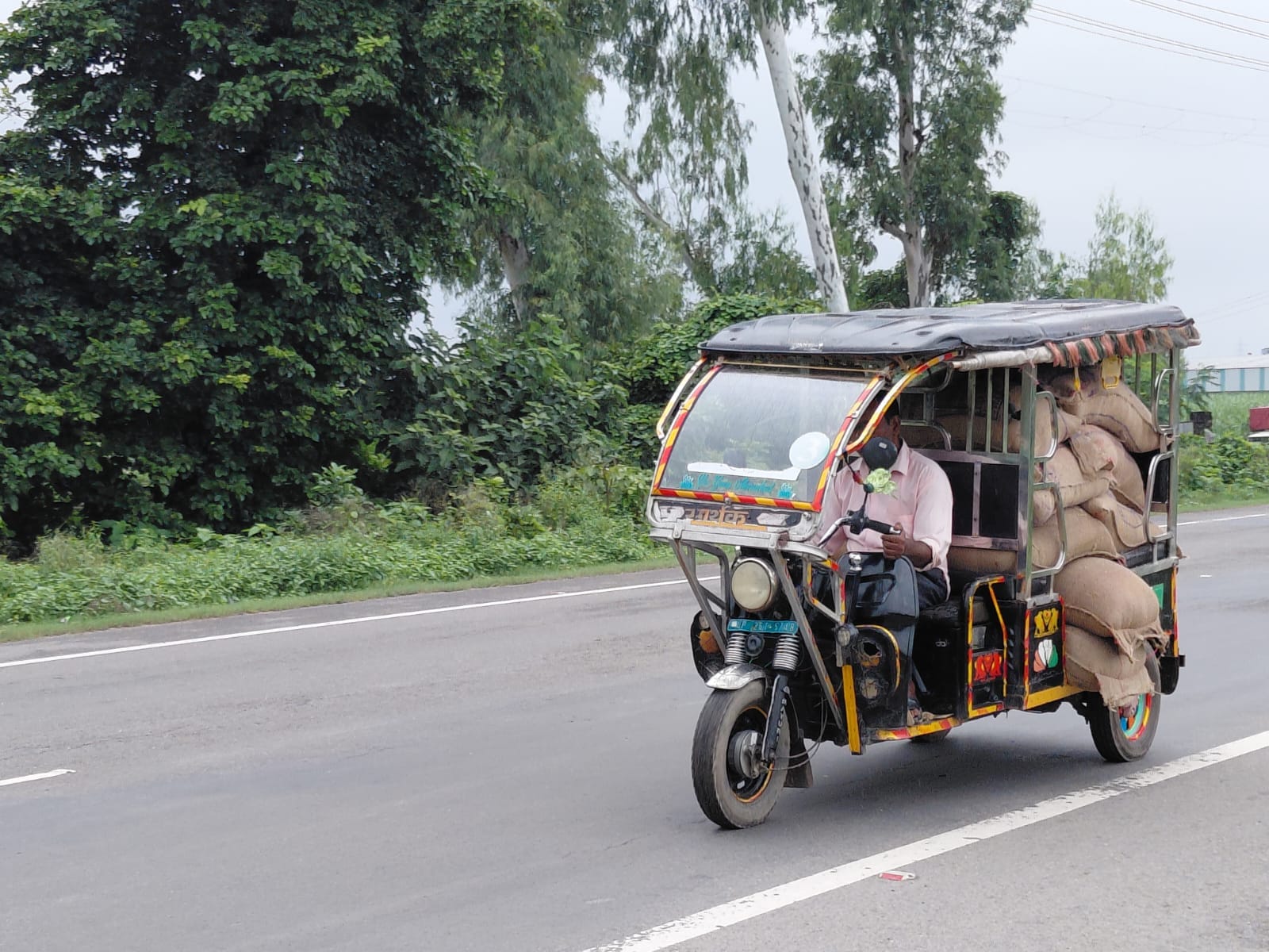 पूरनपुर हाइवे पर बोरियों से लदा अनाज ले जाता ई-रिक्शा चालक। संवाद