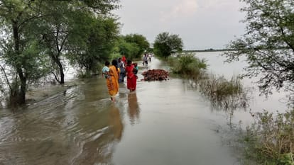 रेवतीपुर-मां कामाख्या धाम पर चढ़े बाढ़ के पानी से बच्चों को गोद में लेकर निकलती महिलाएं। संवाद
