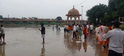 गोमती नदी के घाट पर पानी में खड़े होकर सेल्फी लेते लोग। संवाद