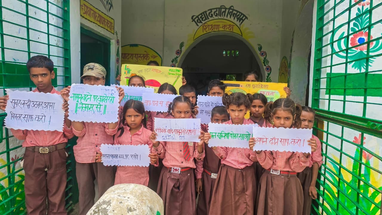 प्राथमिक विद्यालय बगही में जागरूकता कार्यक्रम के दौरान स्वच्छता के स्लोगन लिखे पोस्टर दिखाते बच
