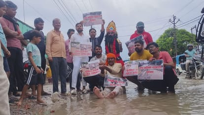 गल्ला मंडी की बादल सड़क पर हुए जलभराव के बीच धरना देकर नगर पालिका के खिलाफ प्रदर्शन करते लोग।