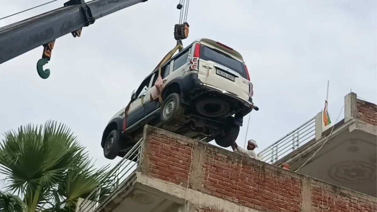क्रेन से छत पर चढ़ाई जा रही स्कॉर्पियो।