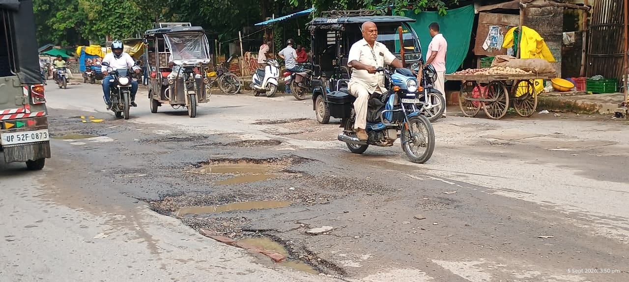 शहर के सिंचाई विभाग चौराहा के पास सड़क पर बने गड्ढों से बचकर निकलते राहगीर। संवाद