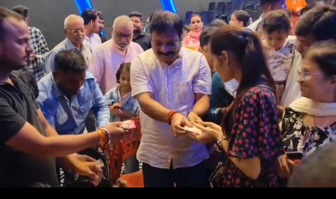 थिएटर में प्रसाद बांटते लोग
