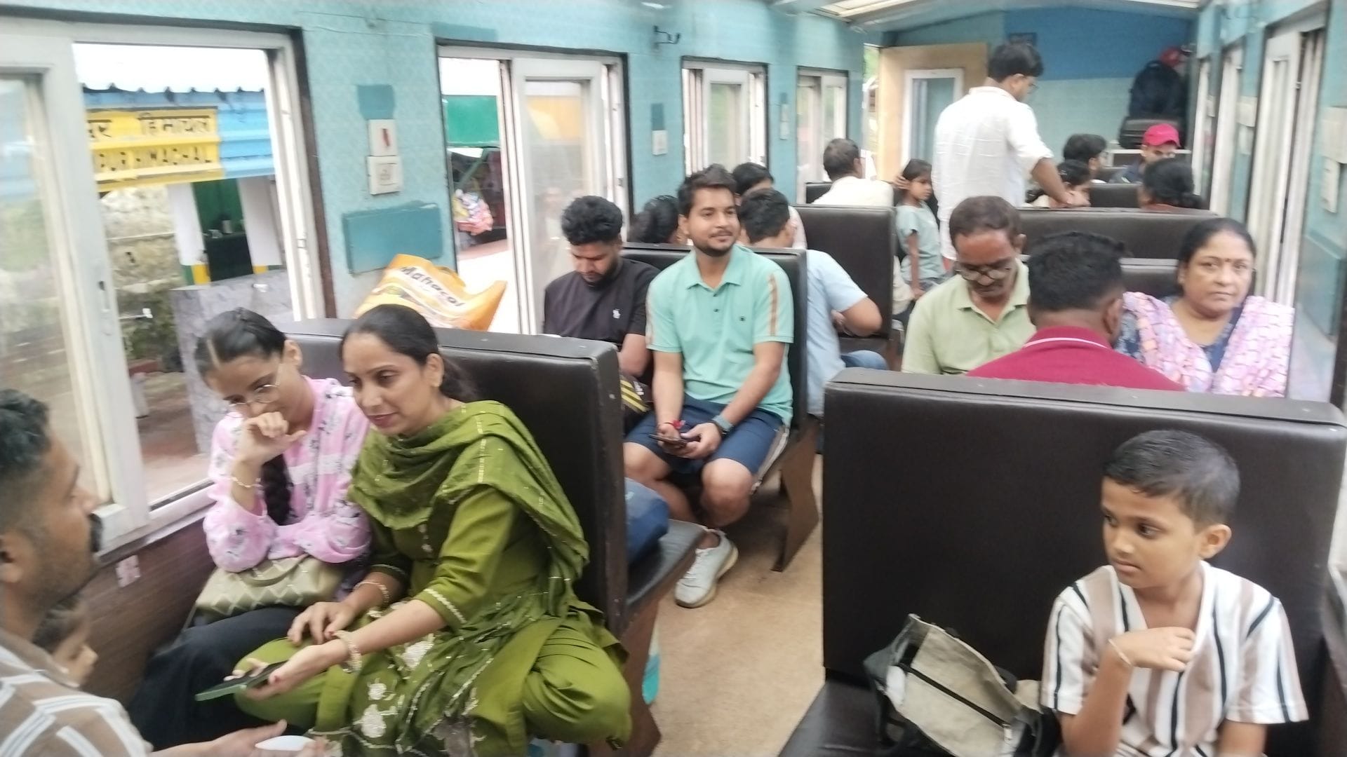 धर्मपुर रेलवे स्टेशन में ट्रेन में बैठे यात्री। संवाद