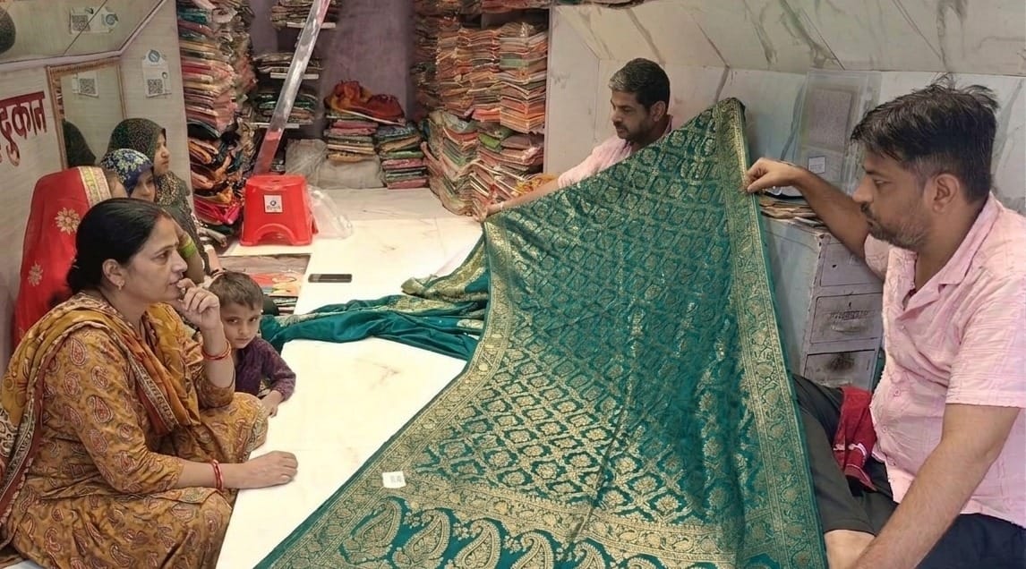 शहर की एक दुकान पर साड़ी दिखाते दुकानदार। संवाद।