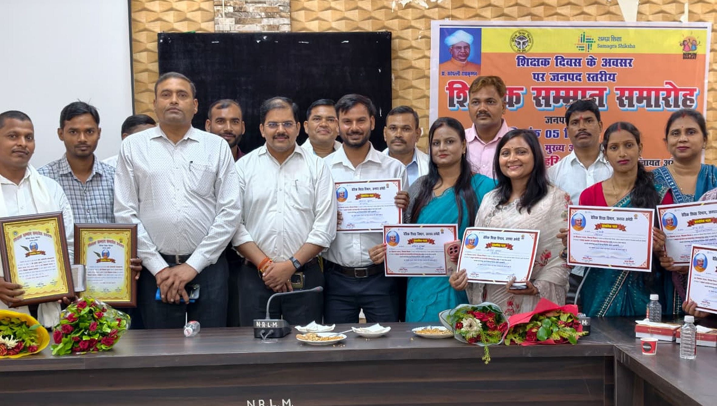 विकास भवन सभागार में आयोजित कार्यक्रम के दौरान प्रमाण पत्र दिखाते शिक्षक। स्रोत: विभाग