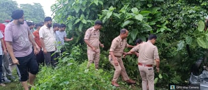असम हाईवे किनारे पानी से भरे गड्ढे में घुसी कार को देखते पुलिसकर्मी और अन्य -संवाद
