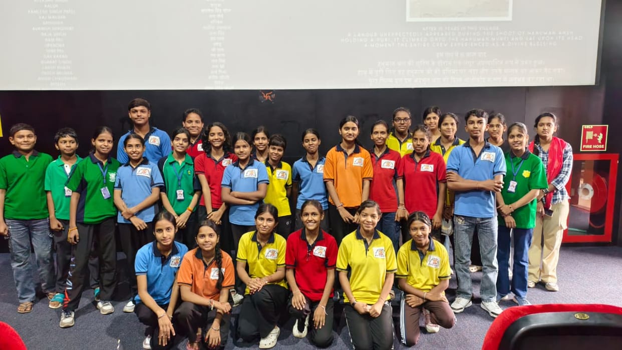 The children watched a movie in the cinema hall; smiles lit up their faces.