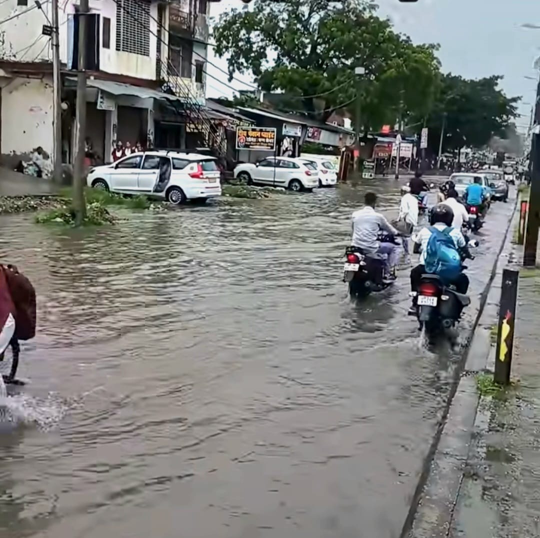 जलभराव के बीच निकलते स्कूली बच्चे व राहगीर। संवाद