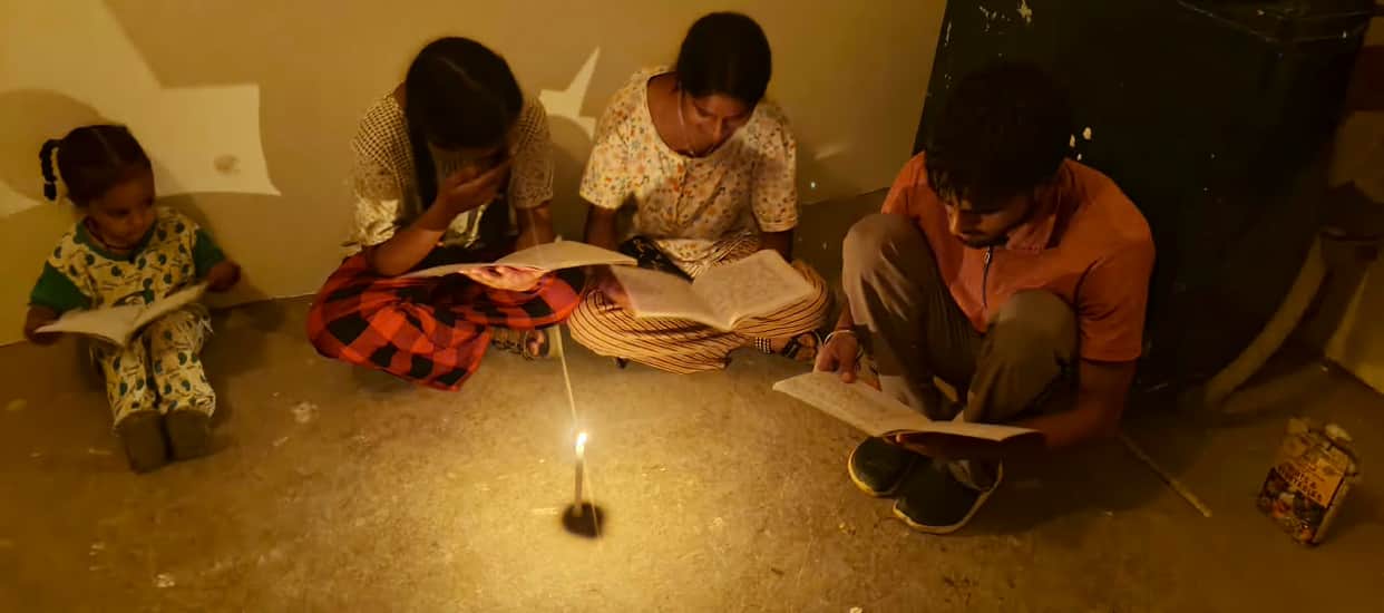 In the chawl, the bulbs merely glow... it is the candle that is providing the light.