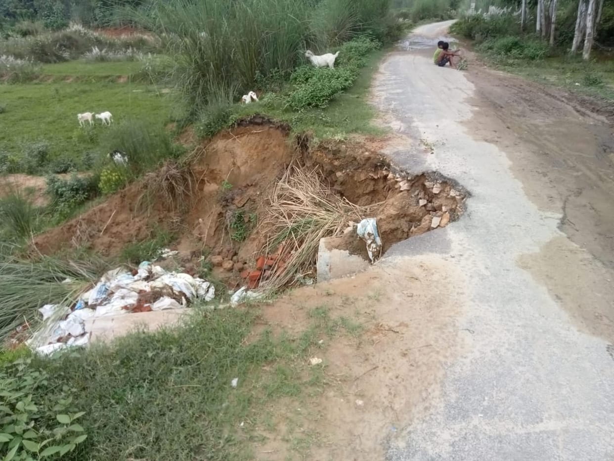 Soil washed away from the paved road; risk of accidents.