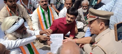 कार्यकर्ताओं संग जमीन पर बैठकर ज्ञापन लेते नायब तहसीलदार मोहम्मद अजीम। स्रोत संवाद