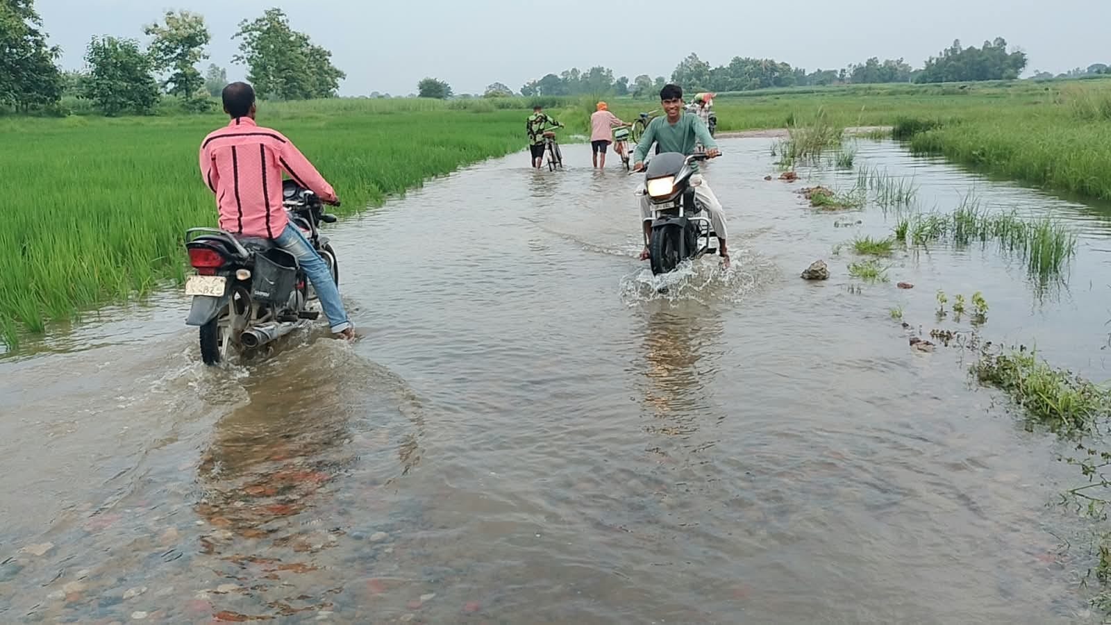 सेमगढ़ा चौराहा-गोविंदपुर मार्ग पर बने अस्थाई बाईपास पर बहते पानी के बीच जान जोखिम में डालकर गु