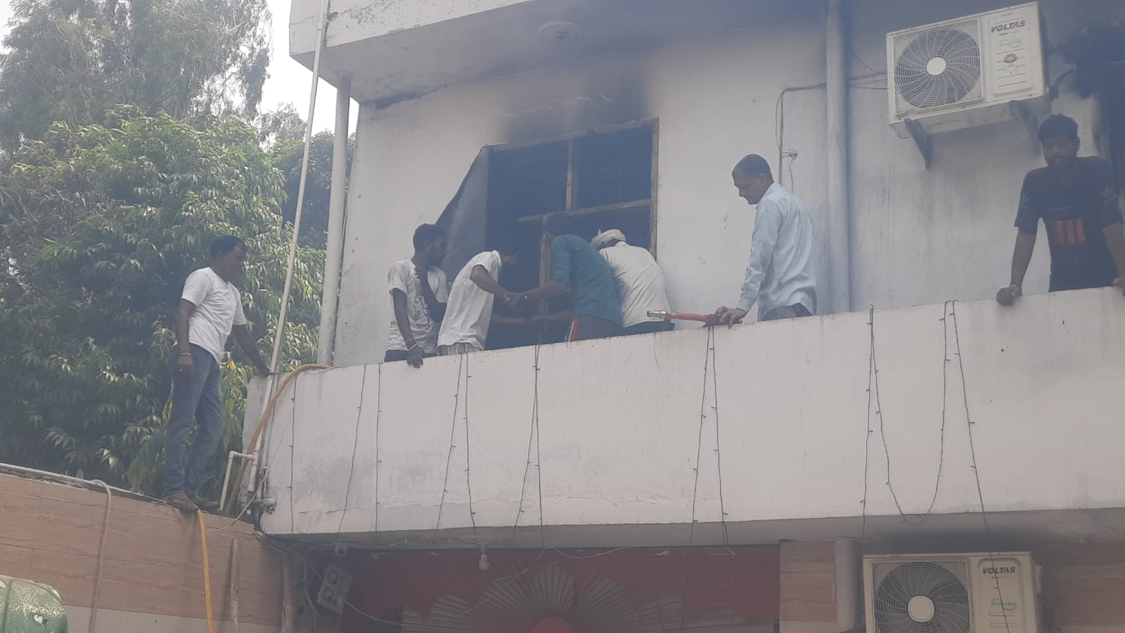 शिव मंदिर में आग बूझाने के लिए खिड़की को तोड़ते कर्मचारी।संवाद