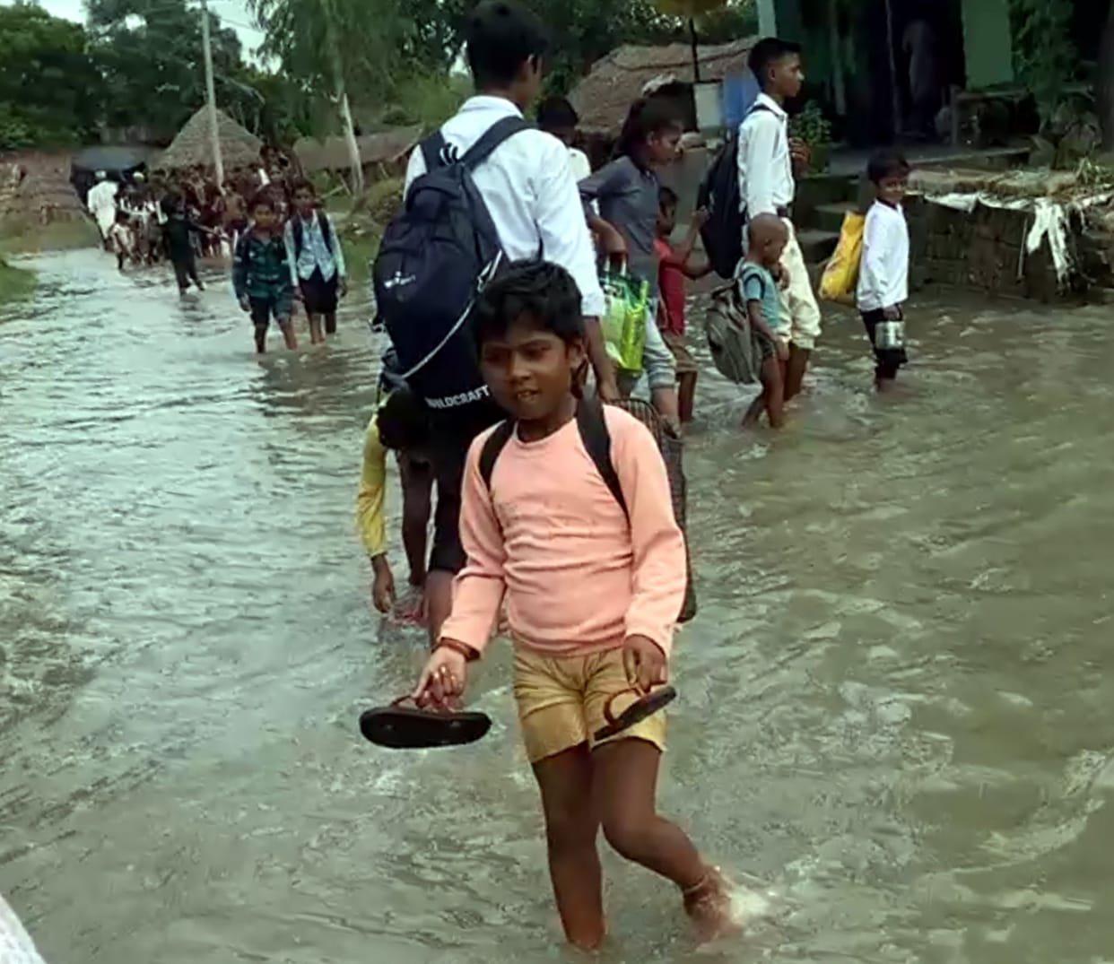 Students heading to school carrying shoes and slippers in their hands and bicycles on boats.