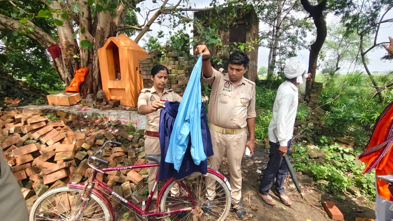 मंदिर के पास मिली साइकिल व ड्रेस को चेक करती पुलिस। संवाद