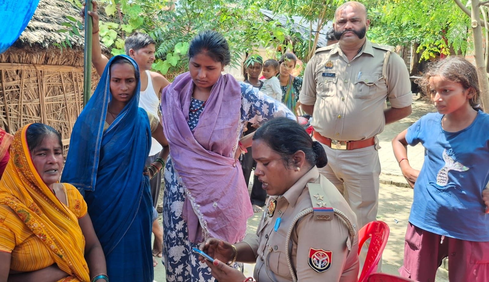 परसपुर के रेक्सड़िया में मृतक विनोद साहनी की पत्नी ऊषा को सुरक्षा का आश्वासन देतीं शाहपुर चौकी इ