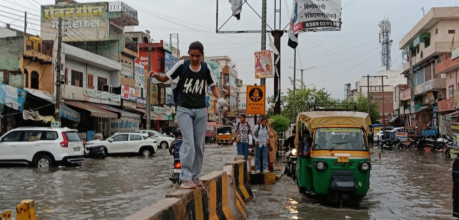 दादरी में शुक्रवार को हुई बारिश से रोहतक रोड पर पानी भरने पर जोखिम उठा डिवाइडर पर चलती युवती। 