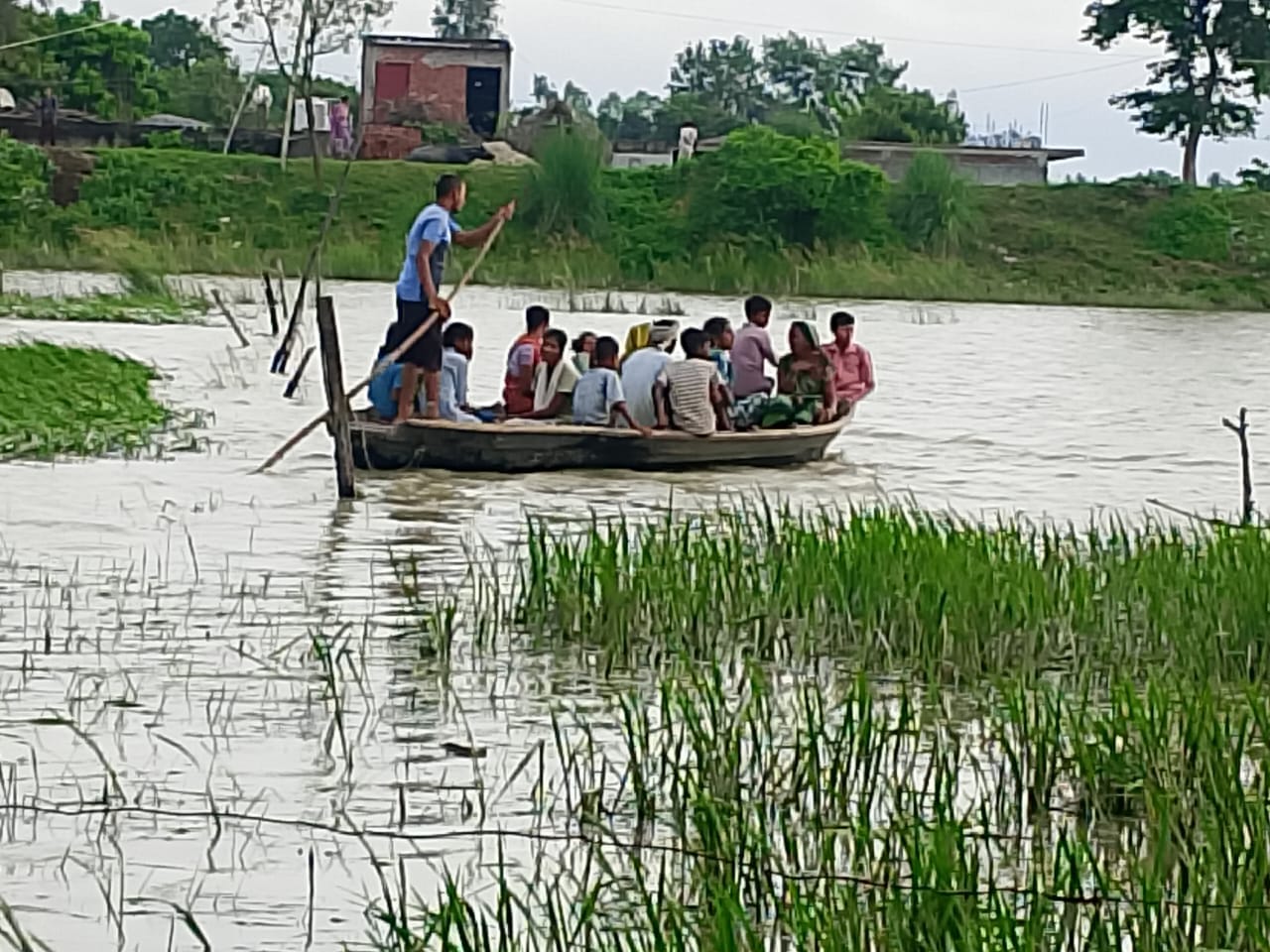 अर्जुनपुर गांव के चारों ओर पानी भरने से तटबंध की ओर नाव से जाते लोग संवाद