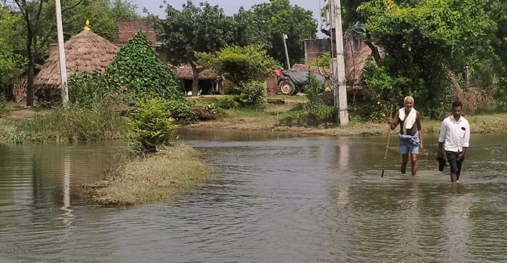 फोटो42पटियाली के गांव नगला जैली में बाढ़ के पानी के बीच से होकर जाते ग्रामीण ।संवाद