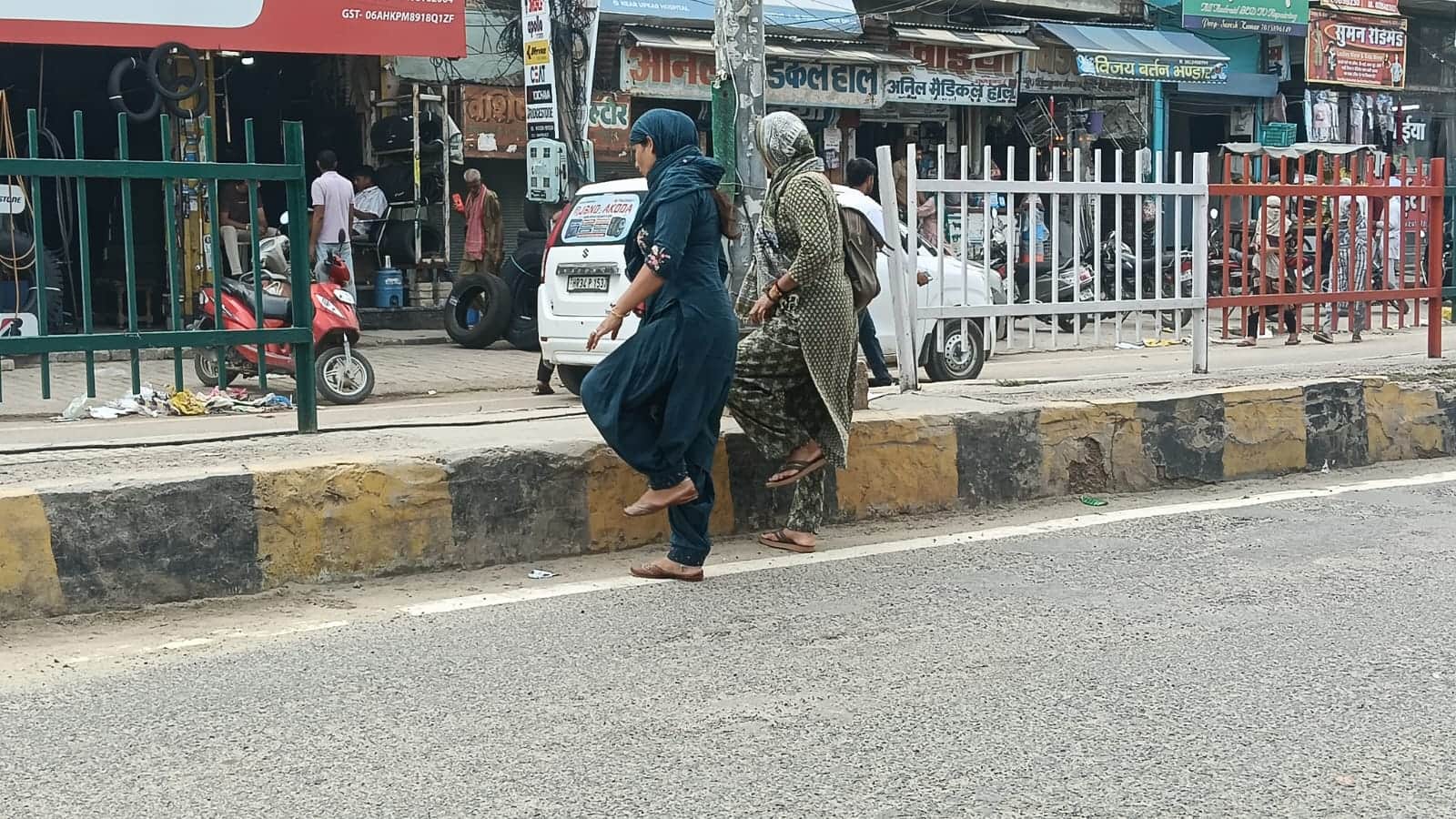 सड़क को पार करने के लिए कट की ओर बढ़ती महिलाएं। 