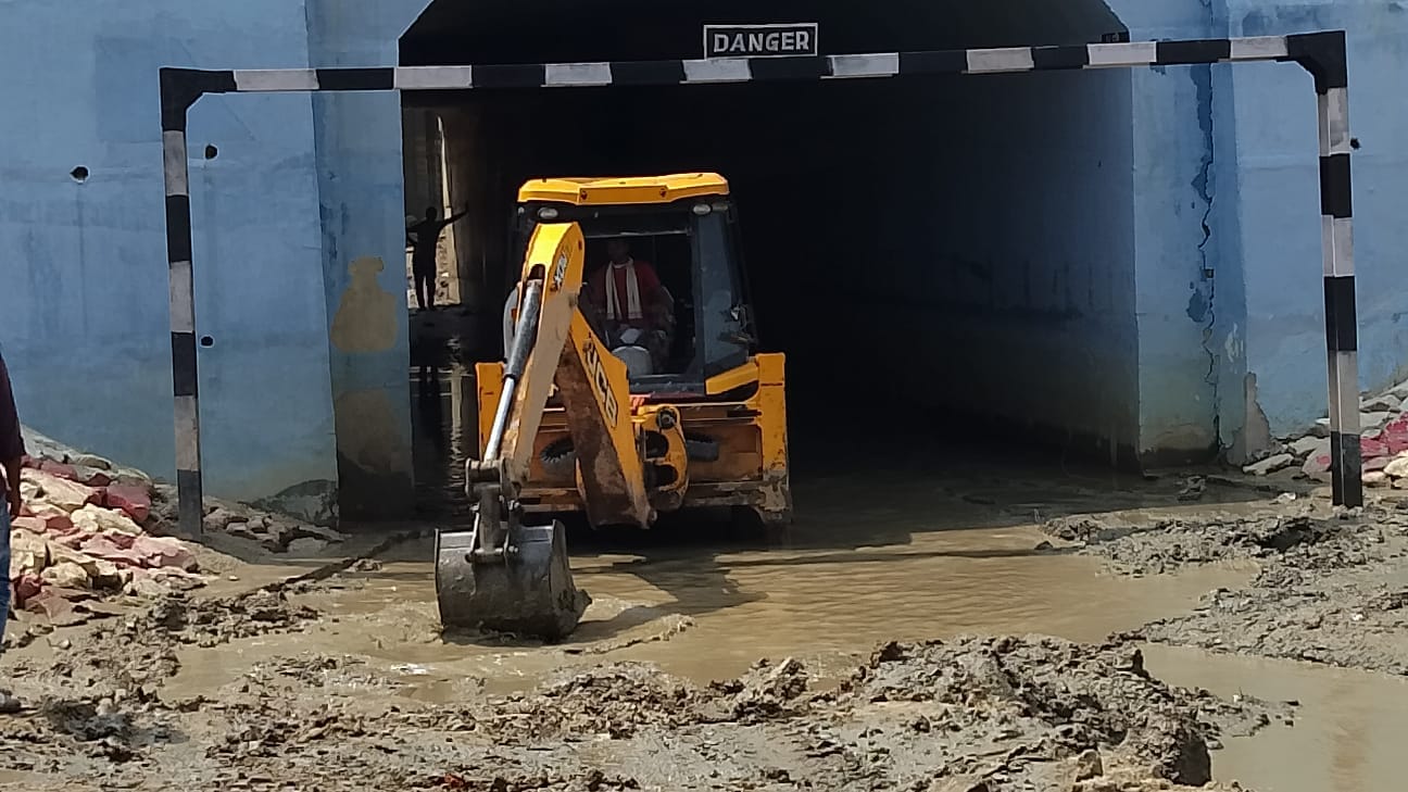 अंडरपास से कीचड़ हटाता जेसीबी, संवाद