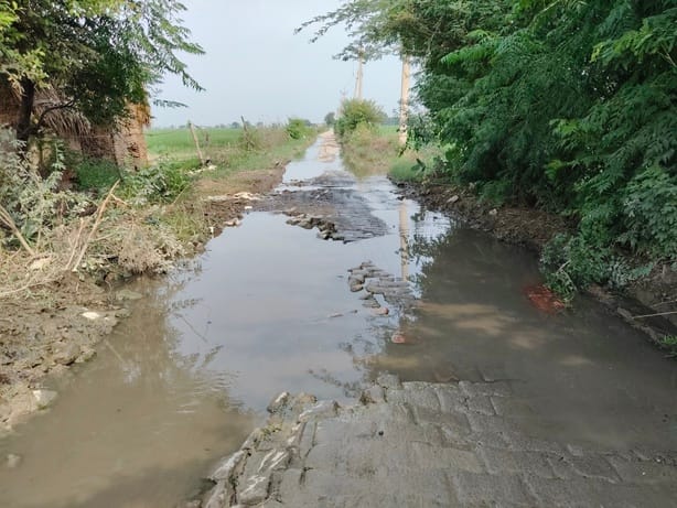 Drainage water flowing onto the dilapidated road.