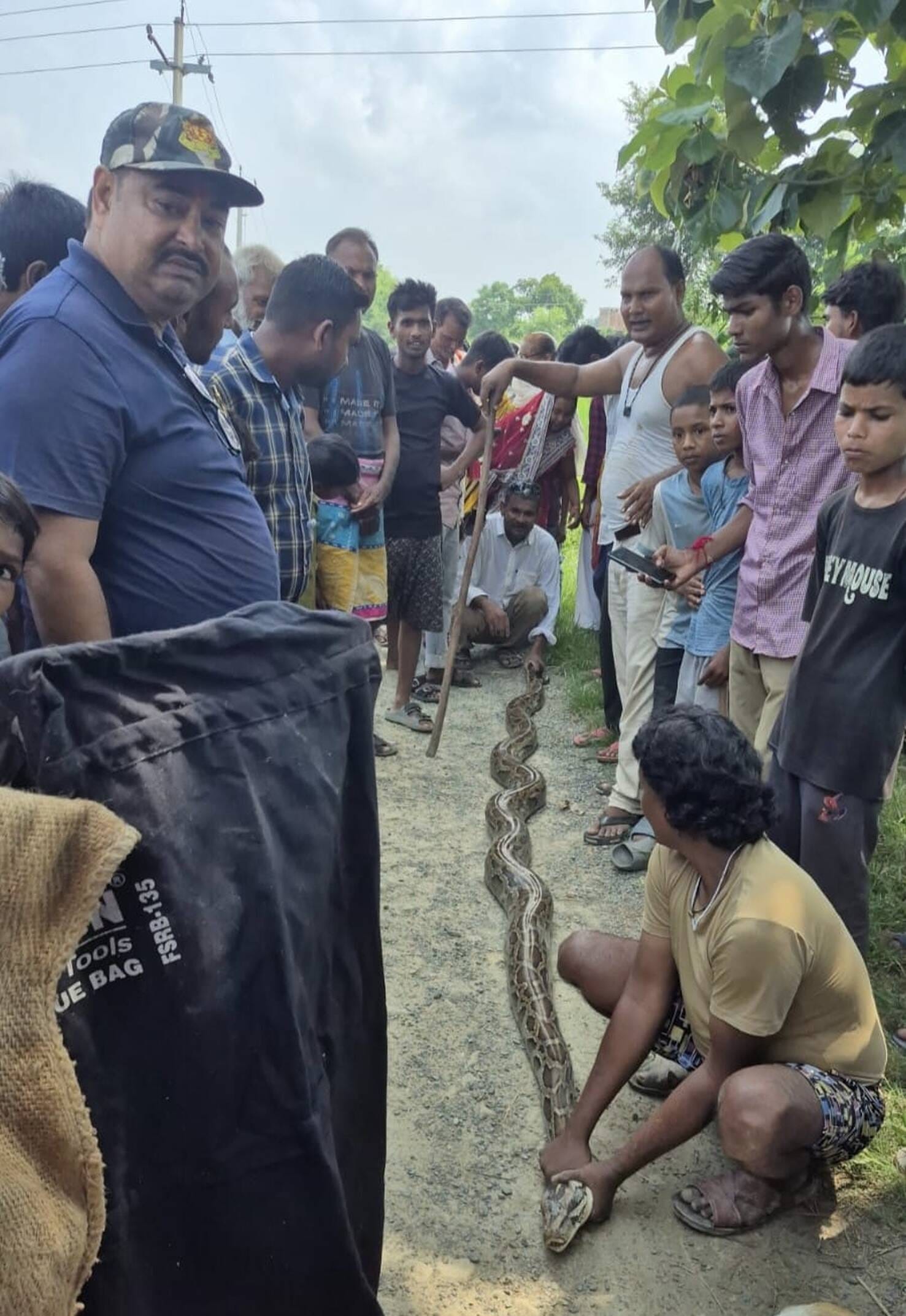अजगर पकड़े व्यक्ति