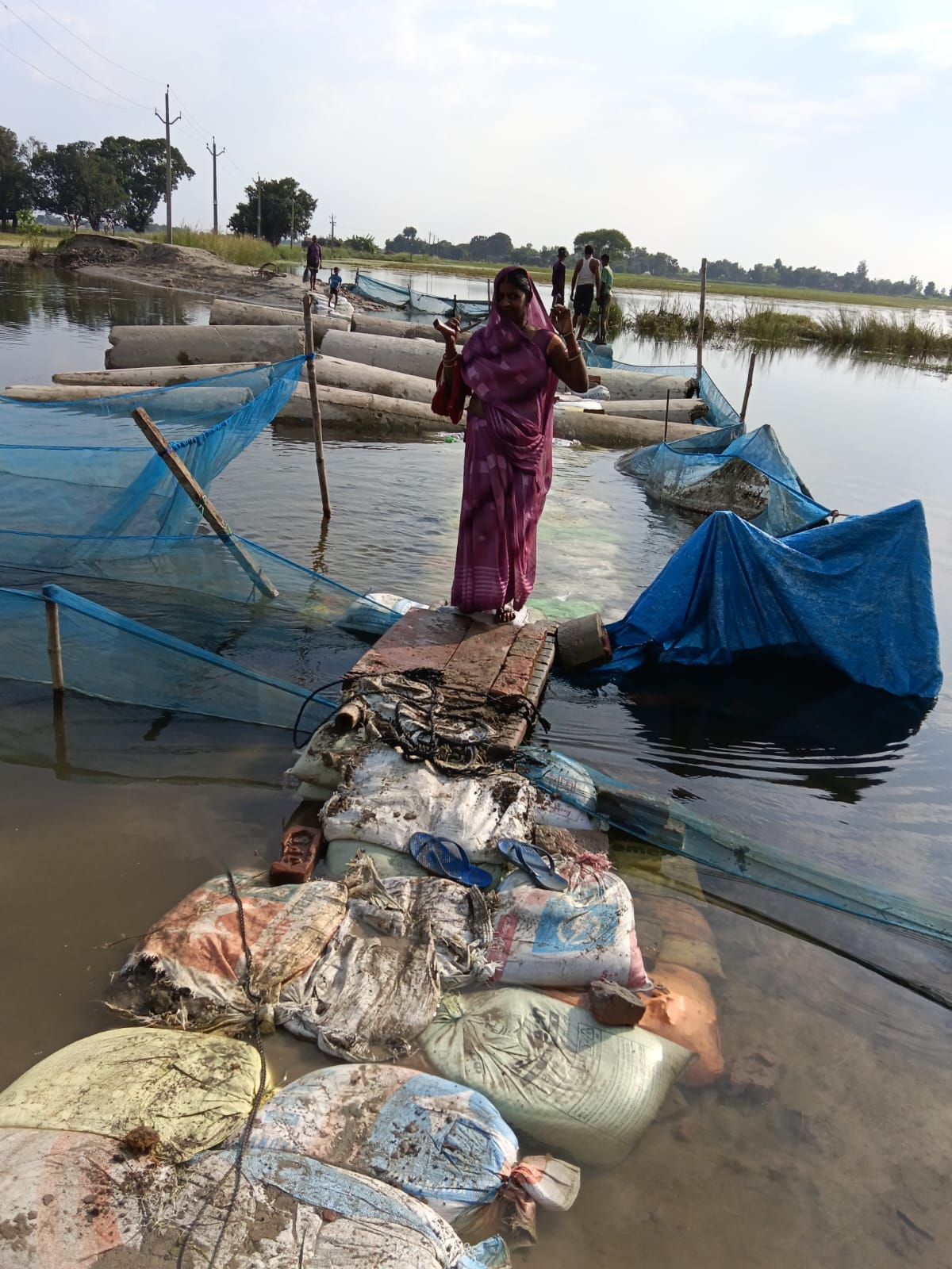 Villagers passing along a path made of sandbags.