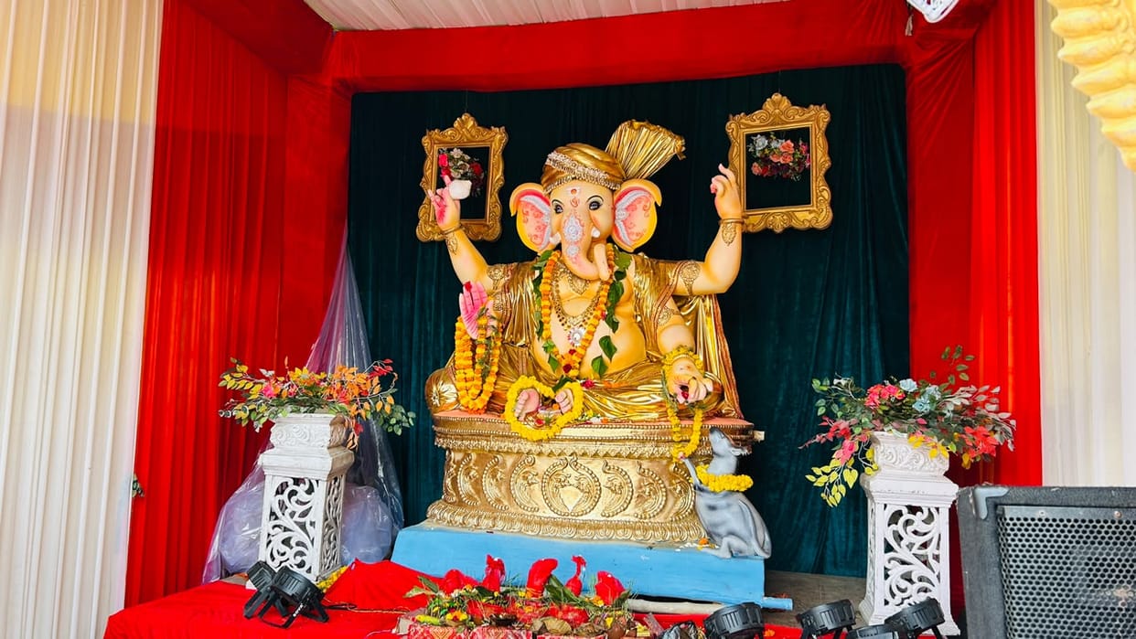 Gajanan sits adorned in a turban; his golden radiance captivates the hearts of devotees.