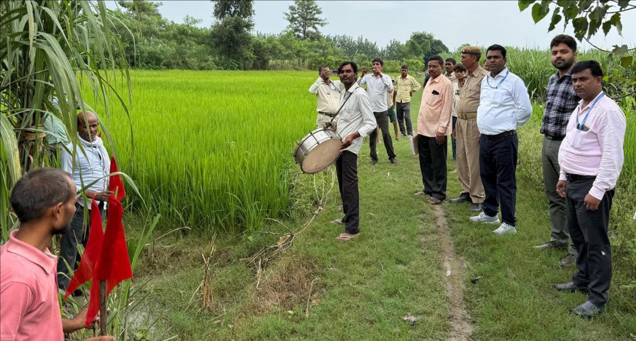 कुर्की की कार्रवाई के दौरान खेत में लाल झंडी लगाती टीम।