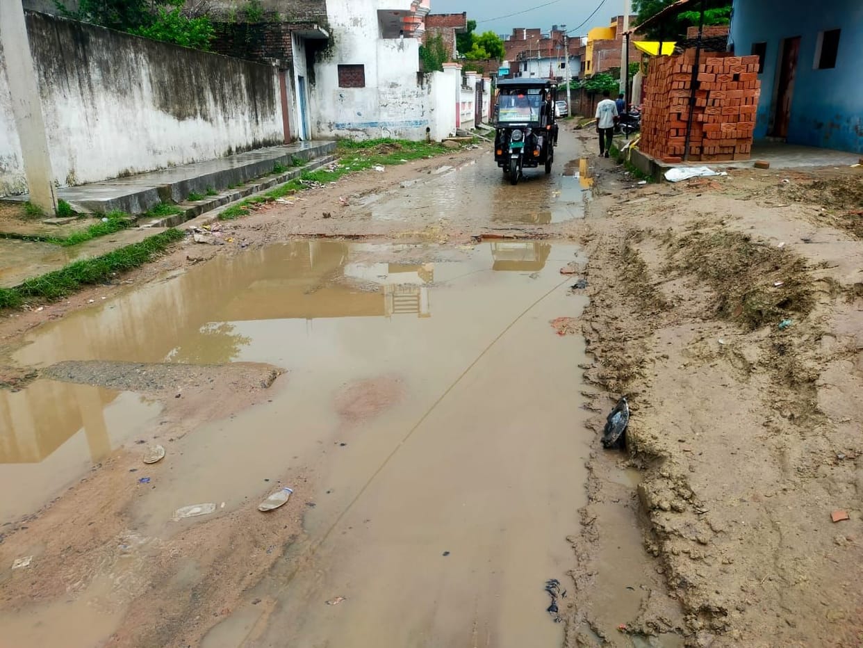 Water from houses flows onto the road on Mendara Marg; passersby inconvenienced