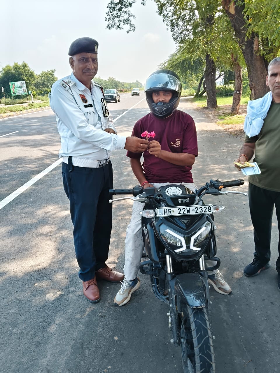 फूल देकर सम्मानित करते हुए पुलिसकर्मी स्त्रोत पुलिस विभाग