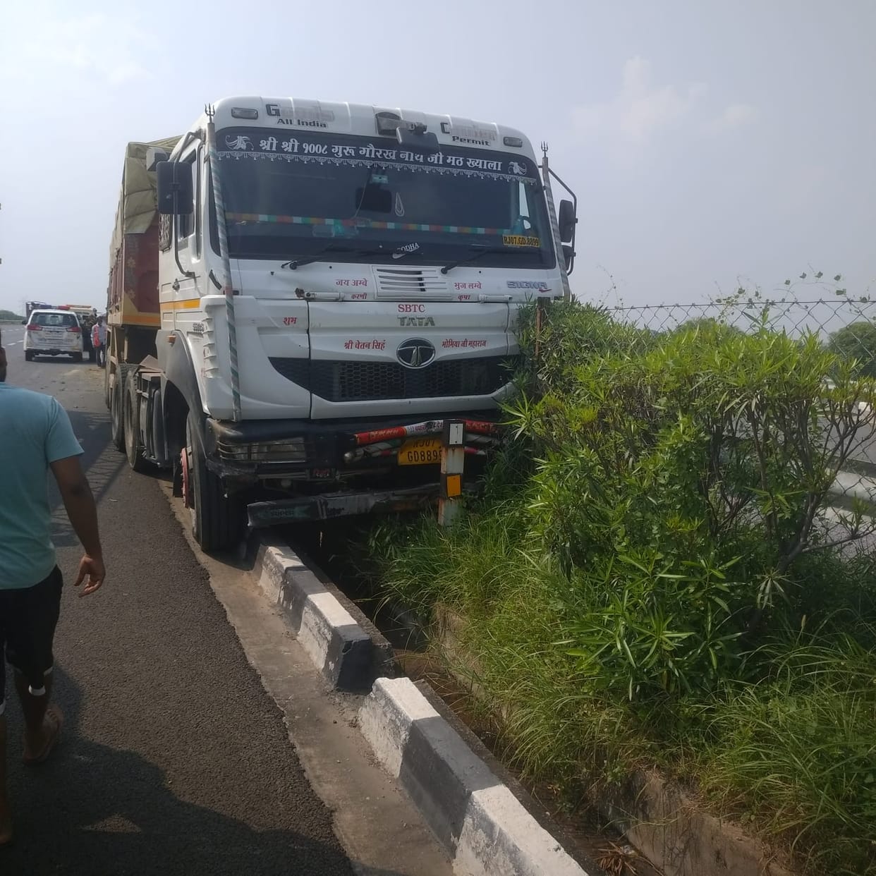 Trailer mounts divider after driver dozes off; driver and helper have a narrow escape.