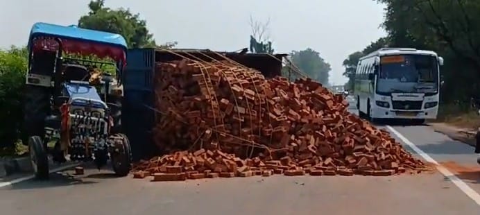Brick-laden trailer overturns on highway; driver has a narrow escape.