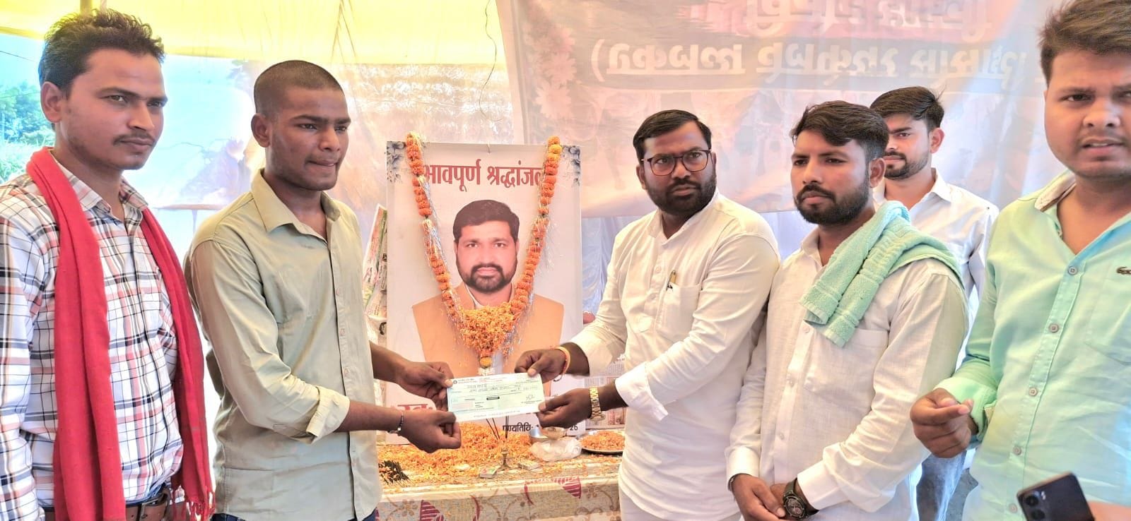 गोंडा के रेक्सड़िया गांव में विनोद साहनी के पुत्र राजा साहनी को चेक देते गोरखपुर के धर्मेंद्र स