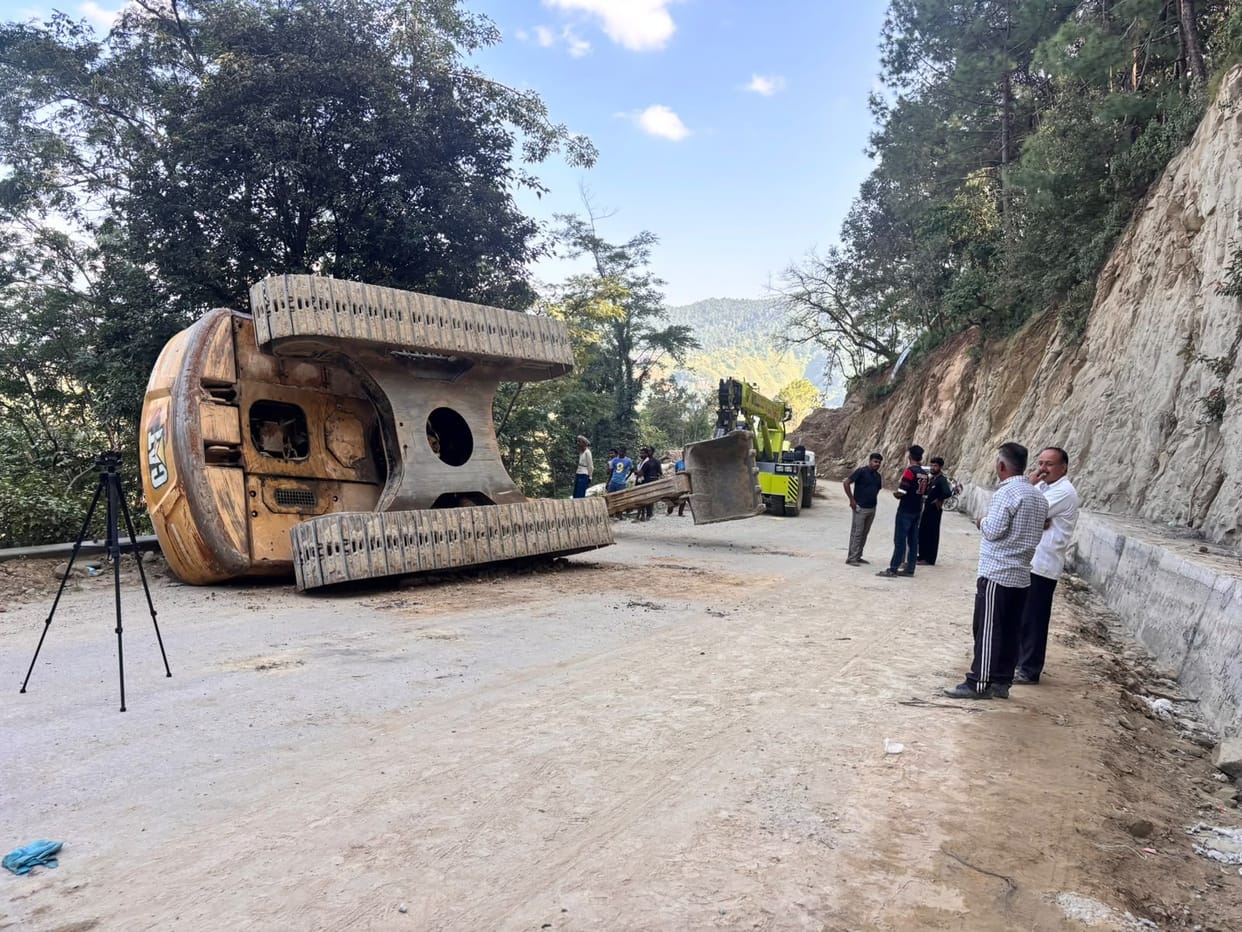 Excavator overturns on road; young operator crushed to death.