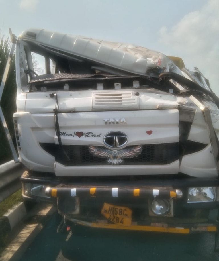 Driver dozes off, truck crashes into barrier; helper injured.