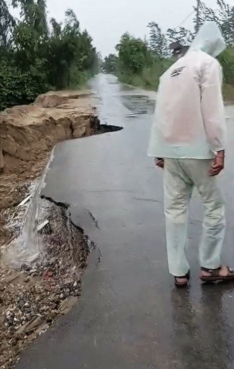 Road caves in due to rain; police set up barricades using bricks.