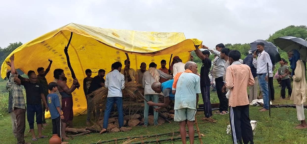Reached the cremation ground via a marshy path; performed the last rites under a makeshift tarpaulin shelter.
