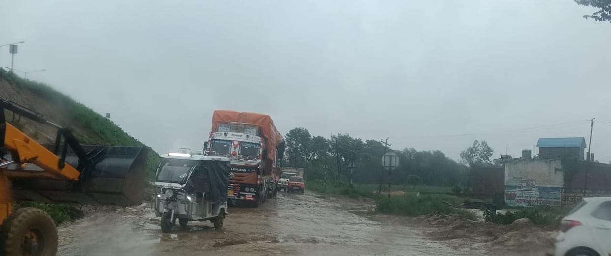 Soil from the highway eroded and spread onto the service road; traffic disrupted due to a fallen tree.