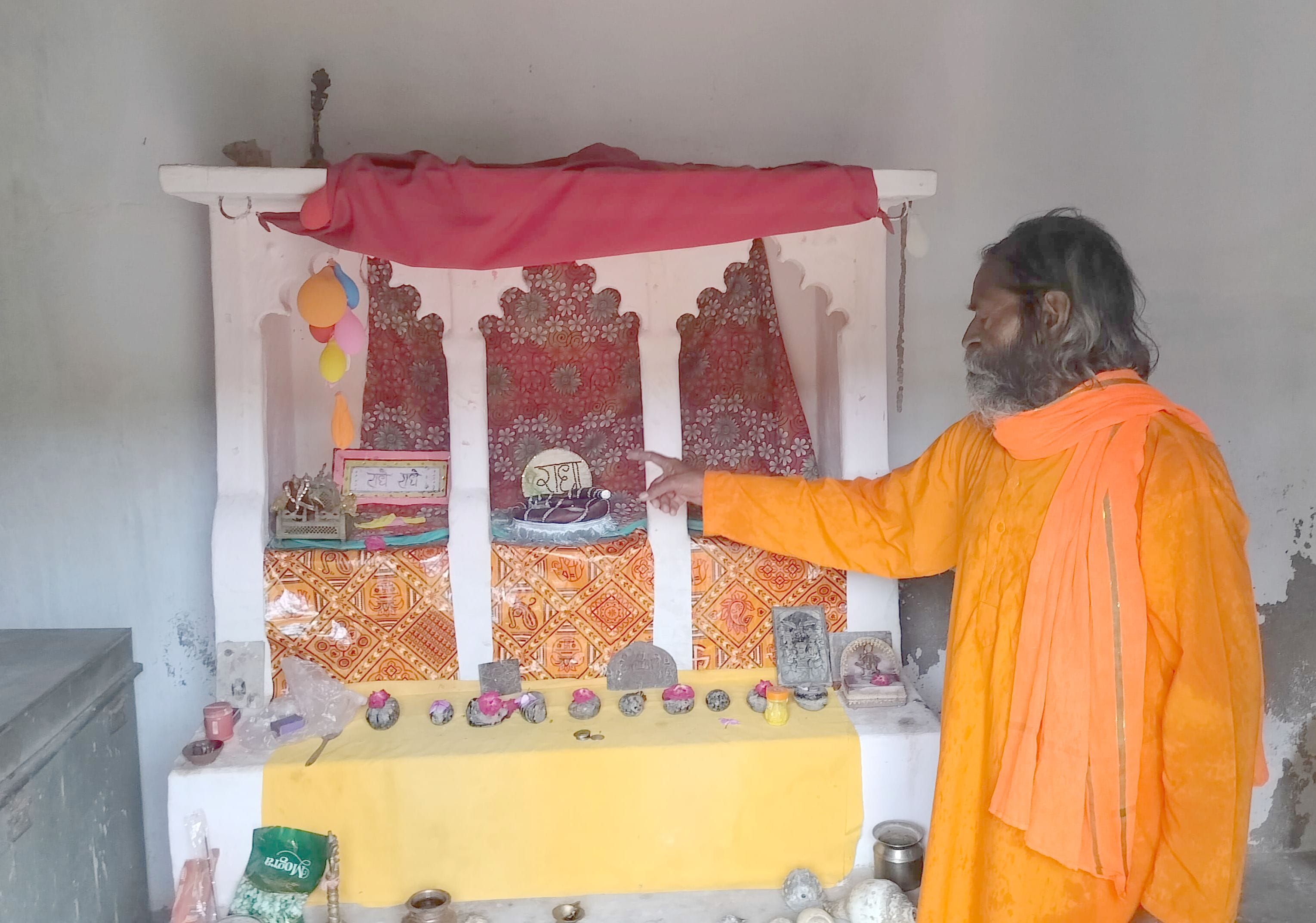 ठाकुरद्वारा में मूर्ति रखे जाने वाले खाली स्थान को दिखाते पुजारी अवध बिहारी। संवाद