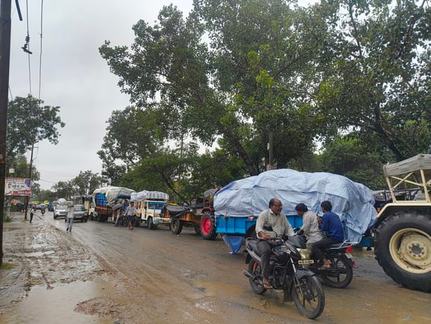 छर्रा मंडी परिसर के बाहर बारिश में कतार में खड़े वाहन। संवाद 