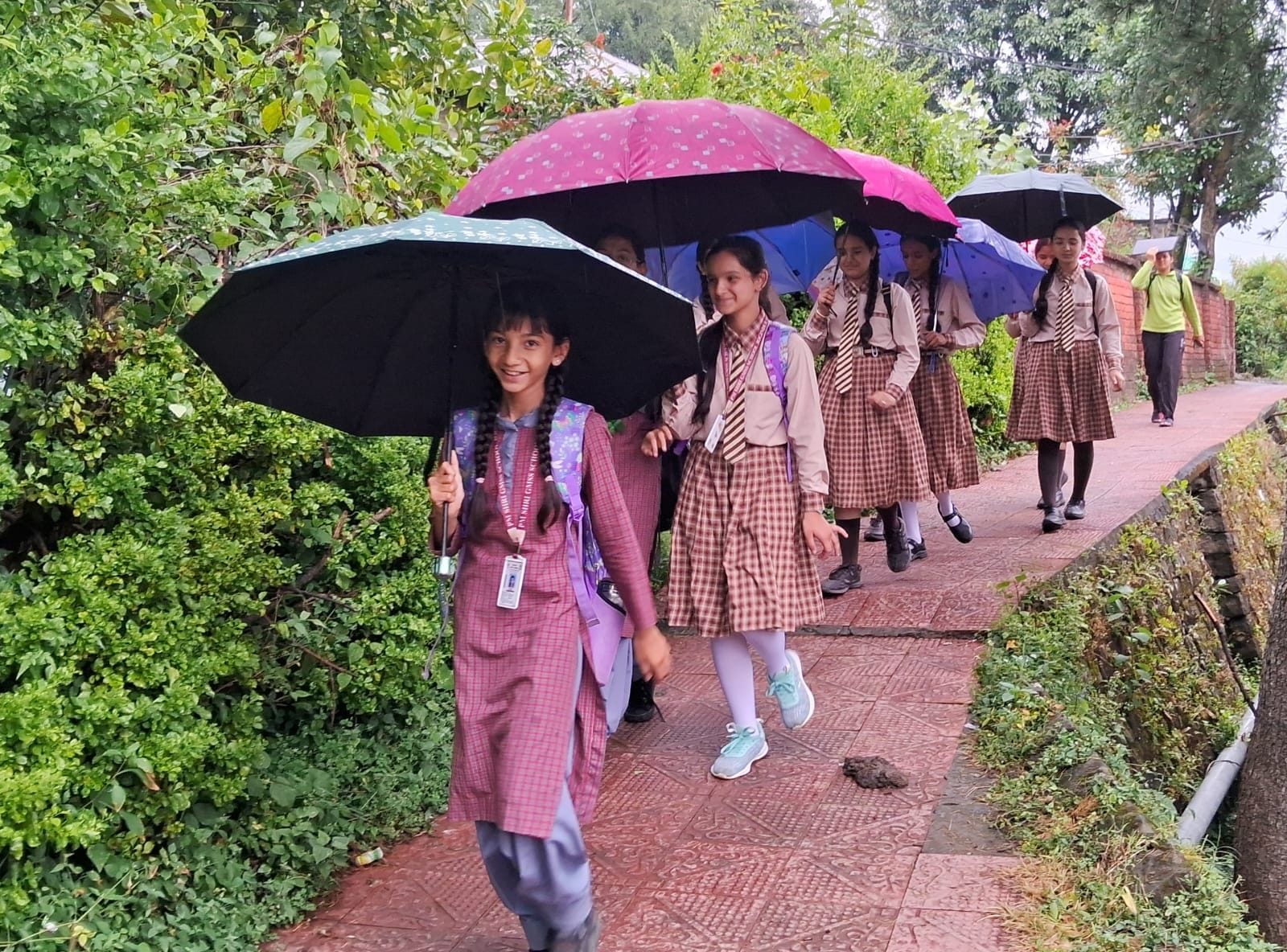 जोगिंद्रनगर में सोमवार सुबह से दोपहर तक जारी वर्षा के बीच छाता लेकर गुजरते शैक्षणिक संस्थानों क