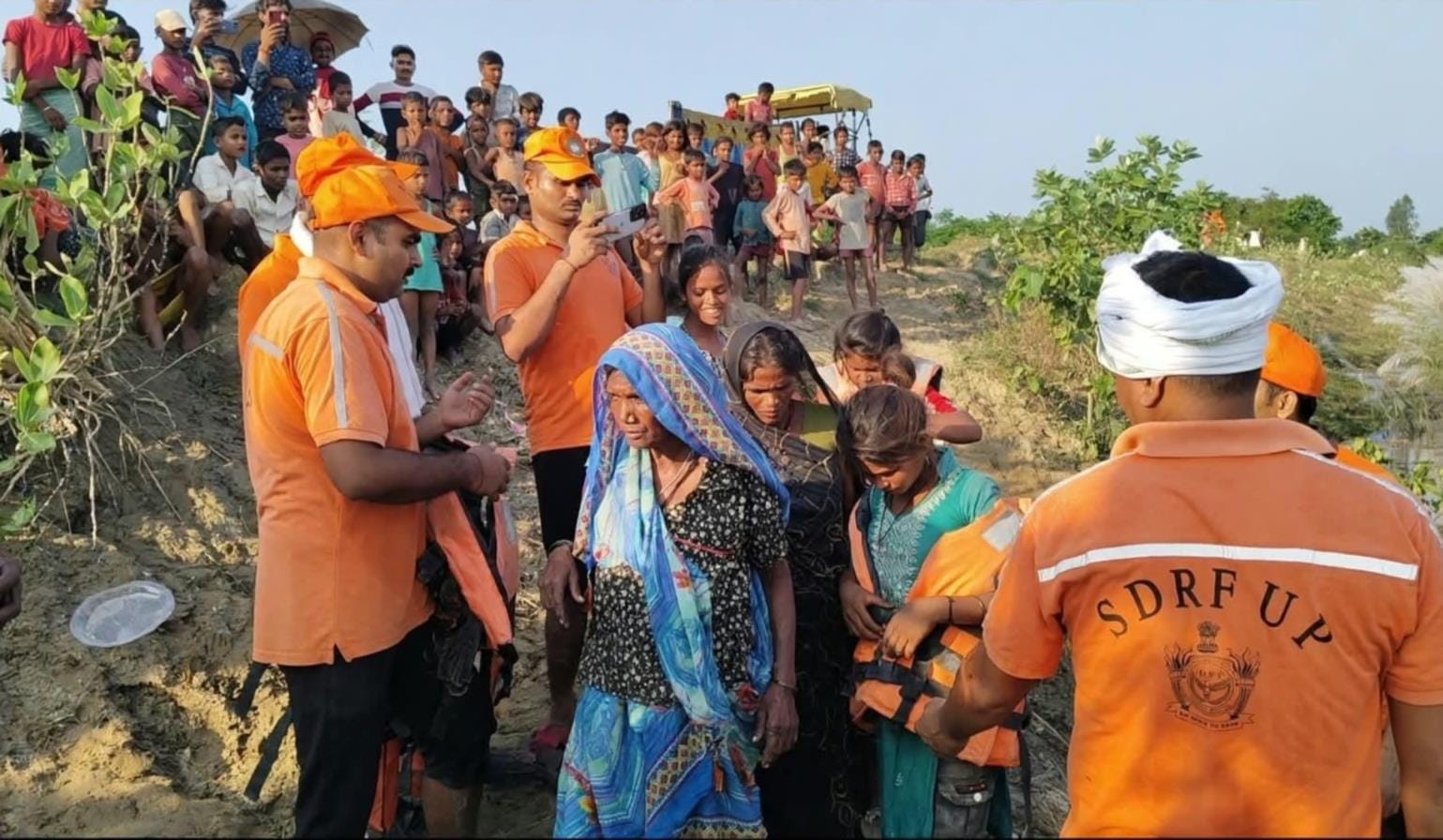  महिलाओं को रेस्क्यू कर नाव से उतारते एसडीआरएफ कर्मी व वीरपुर गांव में भरे पानी के बीच से निकलत
