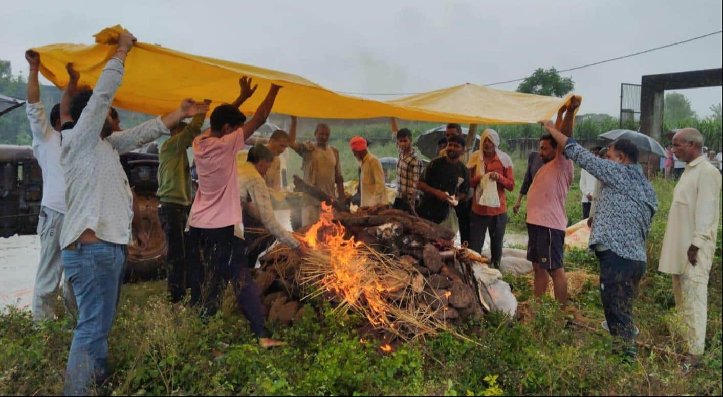 बेबसी... बाबरी में बारिश के दौरान तिरपाल डालकर अंतिम संस्कार करते ग्रामीण। संवाद
